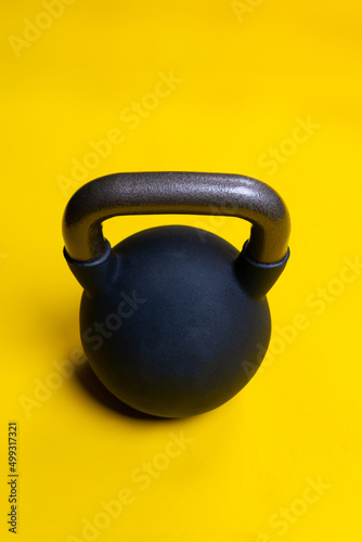 Fototapeta Naklejka Na Ścianę i Meble -  Isolated kettlebell black space yellow ackground fitness cast dumbbell, concept healthy lifestyle gym weight for steel from boxing box, competitive winner. Training hit thai,