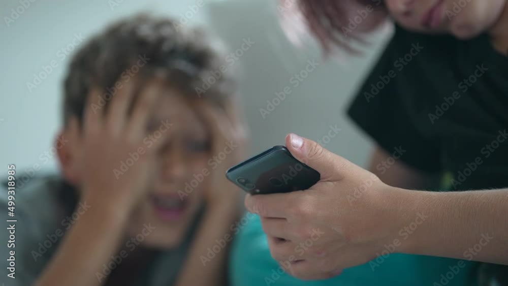 Two teen boys looking at cellphone child reaction with unbelief Two teen boys looking at cellphone child reaction with unbelief