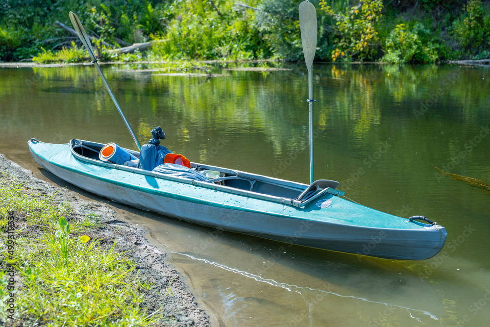 The kayak is moored against the background of the river. Rafting on the fast river. Adventure traveling lifestyle. Concept wanderlust. Active weekend vacations wild nature outdoor. The kayak is moored against the background of the river. Rafting on the fast river. Adventure traveling lifestyle. Concept wanderlust. Active weekend vacations wild nature outdoor.