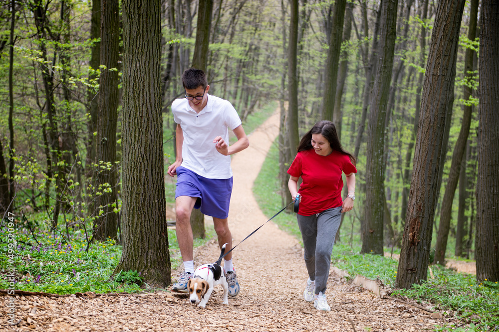 A young girl and a boy runs through the forest with their dog A young girl and a boy runs through the forest with their dog