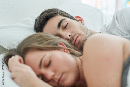 No need to rush today. Shot of a relaxed young couple sleeping in bed together at home.
