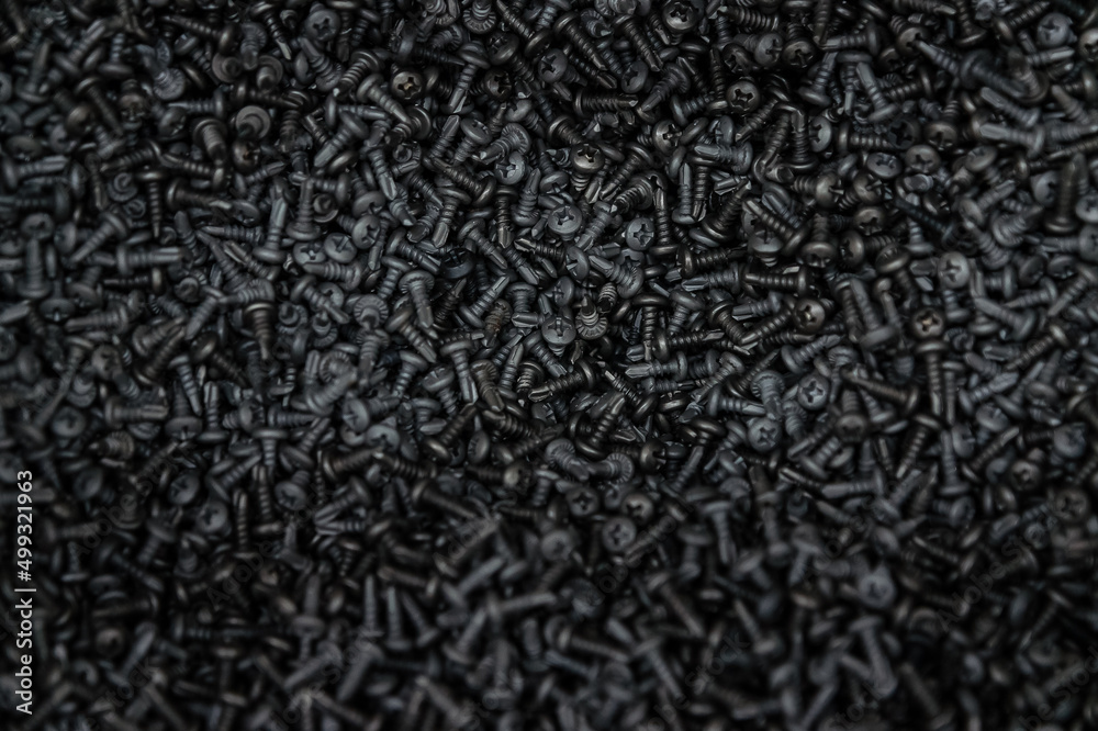 A lot of black bolts with a cross hat. A background of many metal screws A lot of black bolts with a cross hat. A background of many metal screws