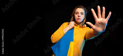 Beautiful Ukrainian girl with the national state flag of Ukraine on black background. Copy space. Russian Ukrainian War. Help and Pray for Ukraine. Stop war.