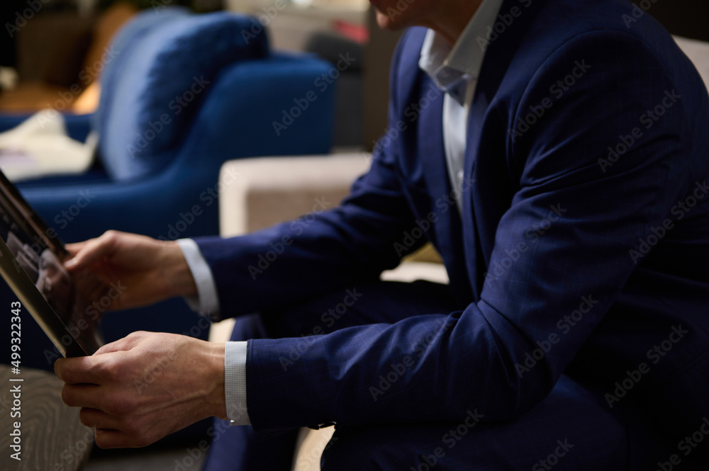 Close-up of male hands holding a catalog with upholstered furniture