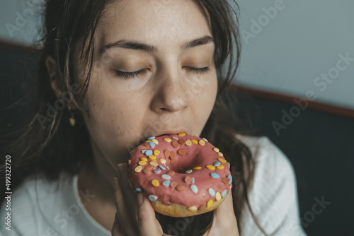 .Close up portrait of pleased pretty girl eating donuts