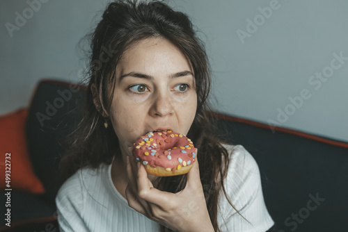 .Close up portrait of pleased pretty girl eating donuts