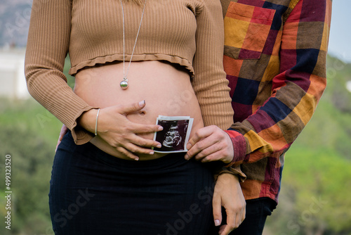 Pregnant couple having ultrasound on green meadow on a spring day. Concept of medical care during pregnancy.