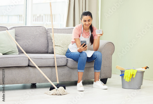 You dont have to do it all in one go. Shot of a woman using her cellphone and drinking coffee while taking a break from cleaning at home. photo