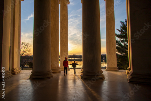 Slika na platnu Children playing near giant pillars at a monument when the sun is setting