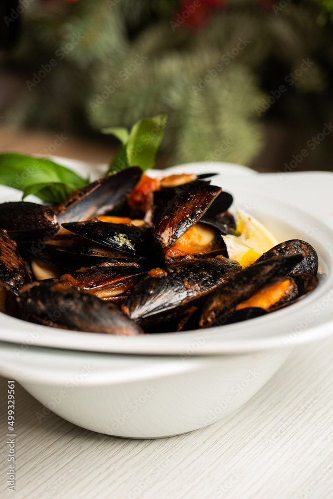 Freshly cooked Seafood Shellfish mussels with cream, wine, cheese sauce and lemon in a white bowl, close-up, studio shot. A classic dish in Belgium, France and Netherlands. Restaurant food. Freshly cooked Seafood Shellfish mussels with cream, wine, cheese sauce and lemon in a white bowl, close-up, studio shot. A classic dish in Belgium, France and Netherlands. Restaurant food.