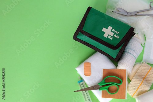 A green first aid pouch with various medical equipment