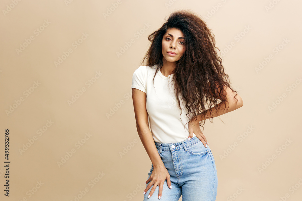 Gorgeous confident curly Latin female look at camera, crossing hands on the chest. Copy space for clothing fashion brands, free place for your ad. Studio shoot isolated over pastel beige background Gorgeous confident curly Latin female look at camera, crossing hands on the chest. Copy space for clothing fashion brands, free place for your ad. Studio shoot isolated over pastel beige background