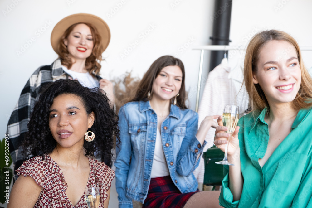 Four beautiful happy women caucasian and african american drinking champagne at home exchange party. Choose casual clothes, shoes, hats, bags, jewelry Four beautiful happy women caucasian and african american drinking champagne at home exchange party. Choose casual clothes, shoes, hats, bags, jewelry