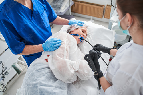 Team of male and female doctors performing gastroscopy in hospital