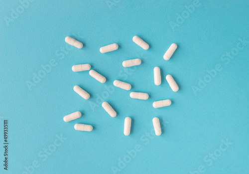 White capsule pills on a blue background. Medical background with copy space for text. 