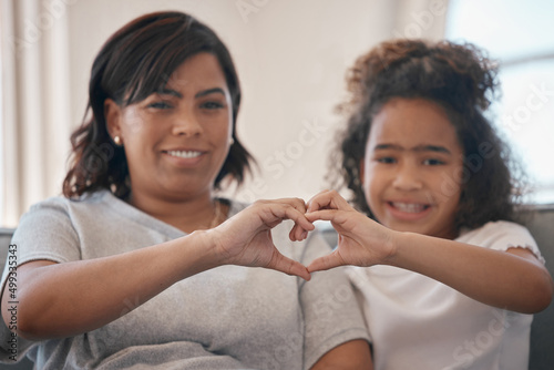Love is always with us. Shot of a young mother forming a heart shape with her daughter at home.