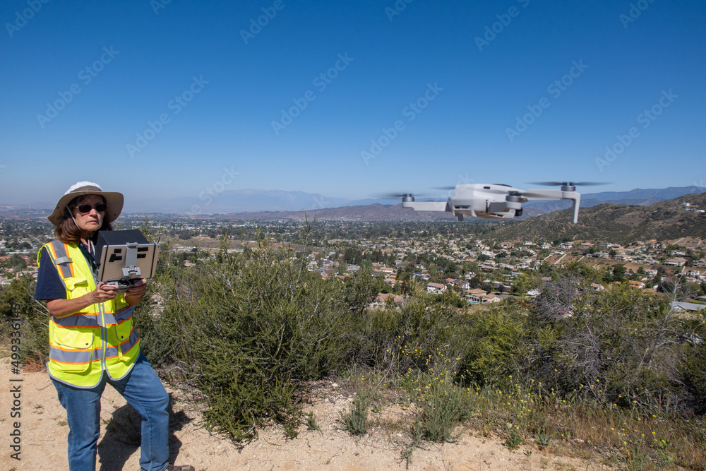 A Woman Certified Part 107 FAA Drone Pilot Conducting an Aerial UAV Survey of a Housing Project A Woman Certified Part 107 FAA Drone Pilot Conducting an Aerial UAV Survey of a Housing Project