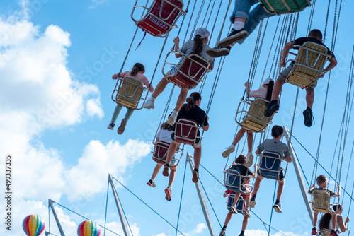Swinging chairs on ride against blue sky

