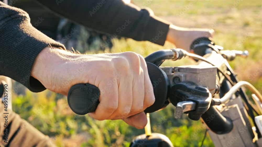Man sitting on enduro motorcycle. Close-up shot of biker hand twisting enduro motorcycle throttle at the pit lane. Preparing for the start of the race Man sitting on enduro motorcycle. Close-up shot of biker hand twisting enduro motorcycle throttle at the pit lane. Preparing for the start of the race
