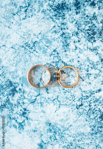 Gold rings on a pastel blue background.