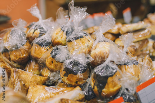 A lot of rum baba cakes with chocolate in polyethylene wrap on supermarket counter. Sweet tasty desserts  delicious food