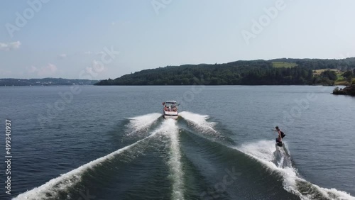A video of waterskiing in the lake district UK on lake windermere. UK 4K drone footage following a speed boat pulling someone waterskiing. Lake UK. English summer. 