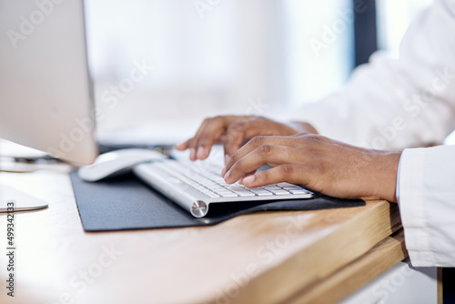 Typing up a few more patient reports. Closeup shot of an unrecognisable doctor working on a computer.