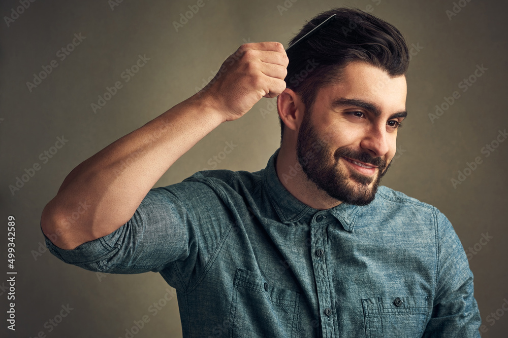 Have you ever seen anything so beautiful. Studio shot of a handsome young man combing his hair against a grey background.