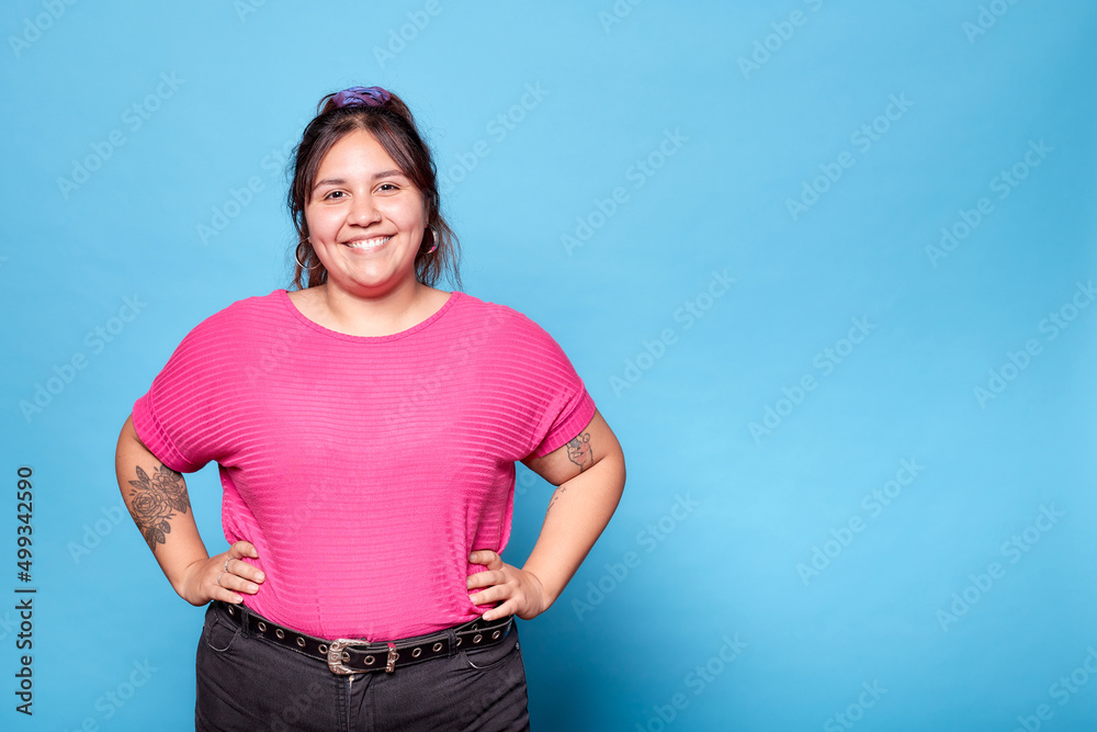 Young curvy latina woman smiling looking at camera isolated on blue background. Copy space. - obrazy, fototapety, plakaty 