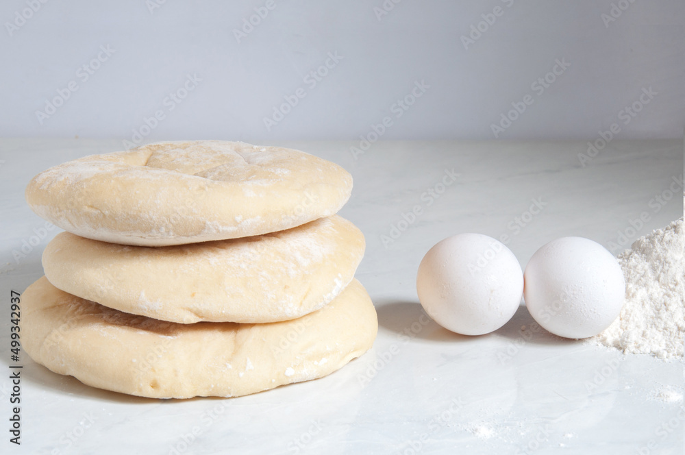 Syrian bread on the table with eggs and flour around Syrian bread on the table with eggs and flour around