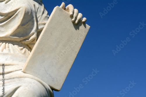 Hand holding granite stone tablet against blue sky