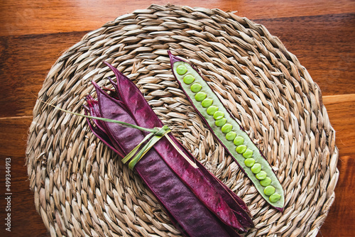 Bundle of purple Guaje bean pods on a plate next to an open bean pod with exposed seeds. Oaxaca, Mexico. photo