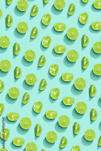 Lime fruit as bring summer food pattern, slices of green citrus with hard shadows at sunlight on pastel mint background. Healthy fruits food concept.  Monochrome flat lay with juicy lime