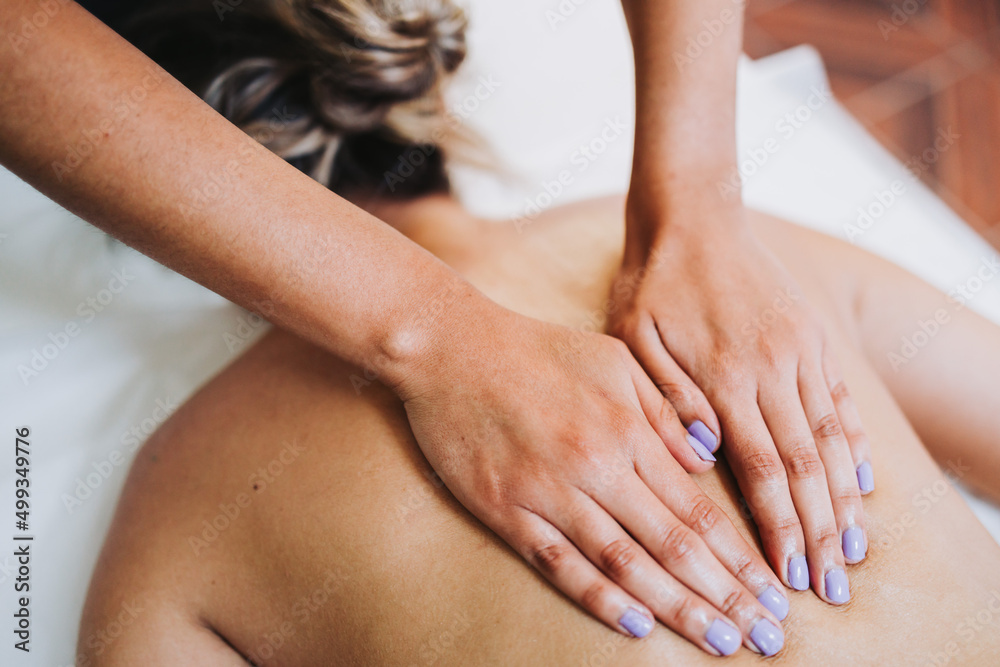 Obraz premium Unrecognizable therapist making higher back and spine massage to a female patient. Relaxing and de-stress