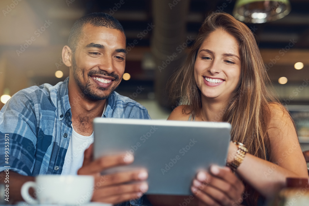 Customers get free wifi in this cafe. Cropped shot of a young couple using a digital tablet while sitting in a cafe. Customers get free wifi in this cafe. Cropped shot of a young couple using a digital tablet while sitting in a cafe.