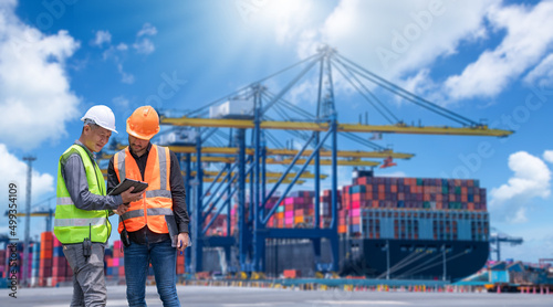Leinwand Poster Engineer wearing uniform inspection and see detail on tablet with logistics container dock cargo yard with working crane bridge in shipyard with transport logistic import export background