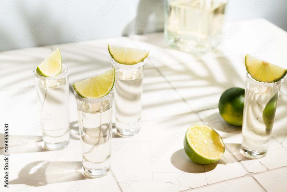 Mexican Gold Tequila with lime and salt on white background with shadows and copyspace. Mexican Gold Tequila with lime and salt on white background with shadows and copyspace.