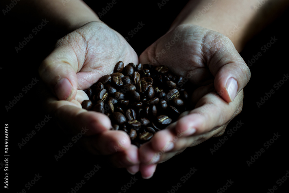 Coffee beans in the hands of heart shaped on wood table dark style Coffee beans in the hands of heart shaped on wood table dark style