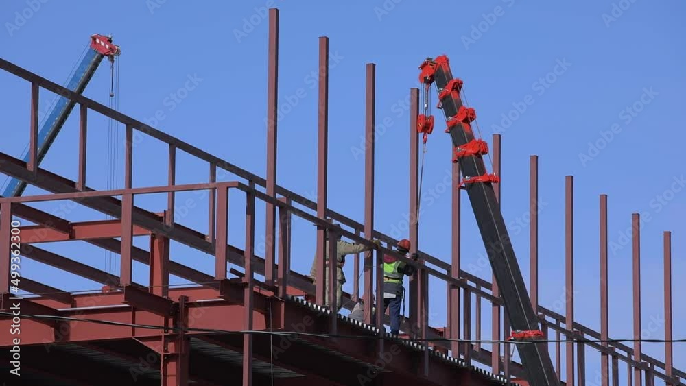Builders fix iron beams with a crane. Frame construction. Builders fix iron beams with a crane. Frame construction.