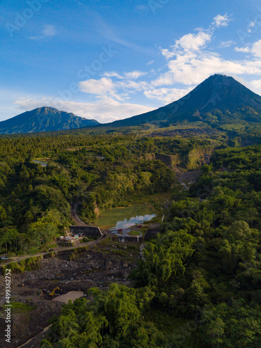 The view of Mount Merapi with the Bebeng River and a lake that holds water, the sky looks cloudy. Forest with dense of trees surrounding the lake also See Mt. Merbabu from a distance. Bego Pendem photo