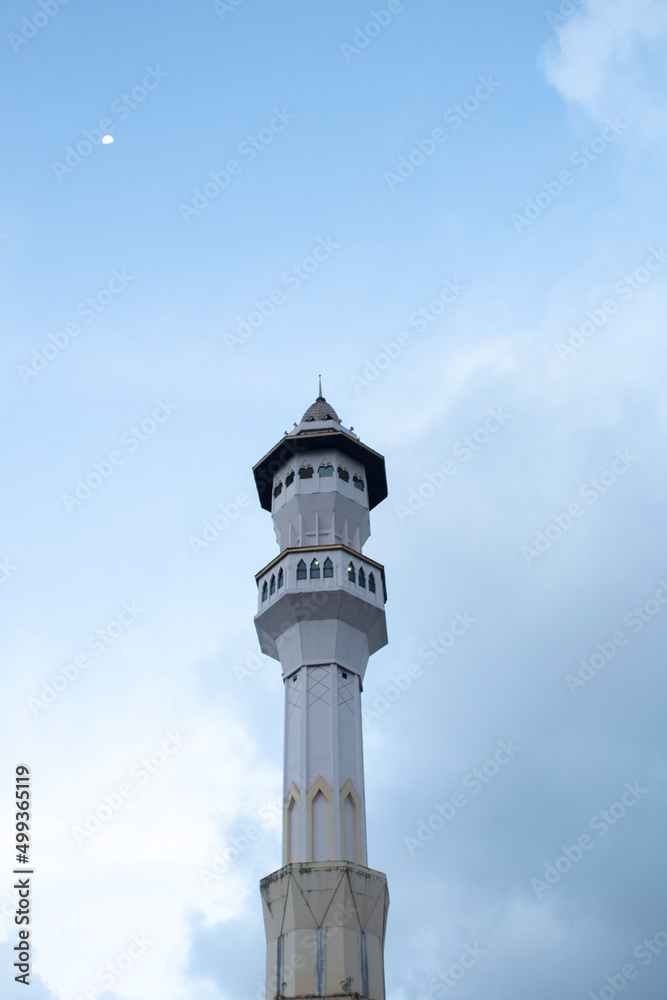 Mosque minaret and moon with clear sky in the afternoon