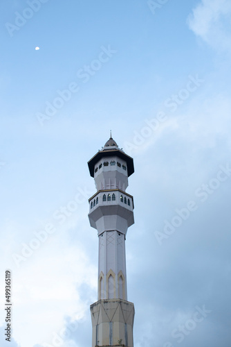 Mosque minaret and moon with clear sky in the afternoon