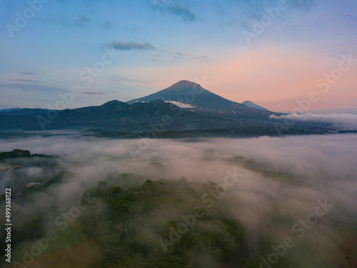 The mist in the morning covered the plains so that the trees were obscured. Seen the view of Mount Sumbing in the distance