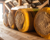 Insulation rolls in yellow packaging in the attic of a wooden house. r