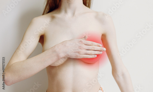 A woman checks with her hand for signs of breast cancer on a gray background. The concept of health care for women's breasts.