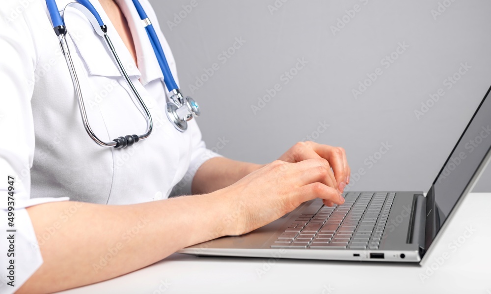 Doctor hands closeup using laptop for typing diagnosis, medication prescription, treatment recommendations . Woman in lab coat sitting at table with computer and stethoscope. High quality photo Doctor hands closeup using laptop for typing diagnosis, medication prescription, treatment recommendations . Woman in lab coat sitting at table with computer and stethoscope. High quality photo