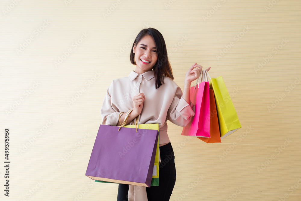 Woman holding paper bags on yellow background.