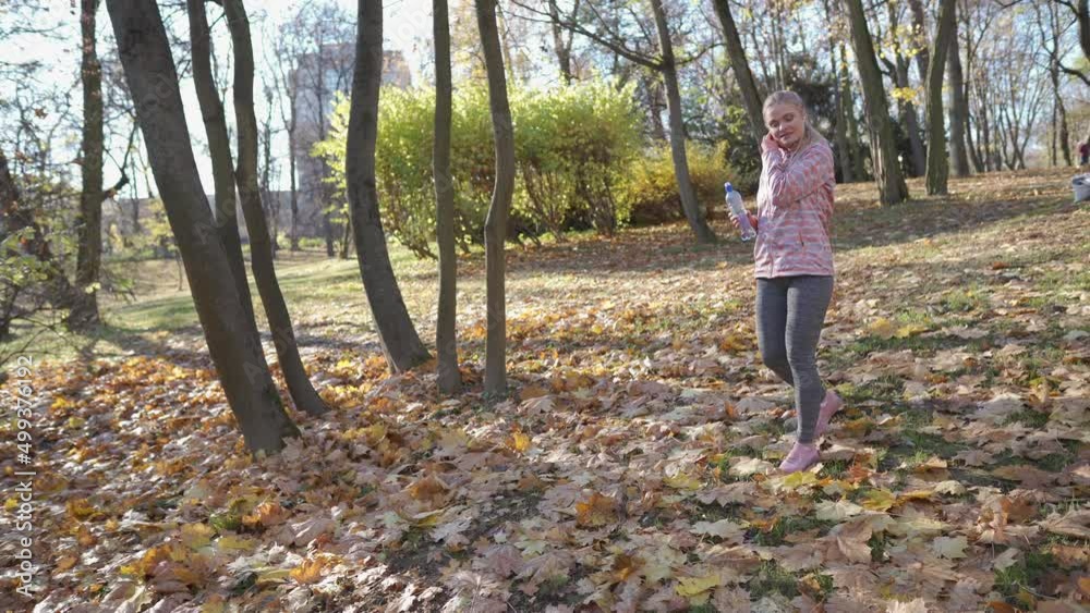 A girl walks in the park and corrects the headphones in her ears. A girl walks in the park and corrects the headphones in her ears.