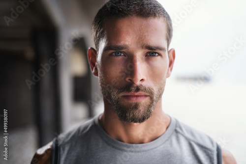 Hes not playing ant games about his fitness. Portrait of a handsome young sportsman looking serious while exercising outdoors.