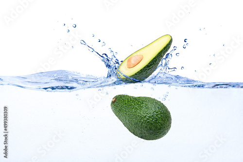 Fresh avocado with cut in half sliced falling in water with splash isolated on white background.